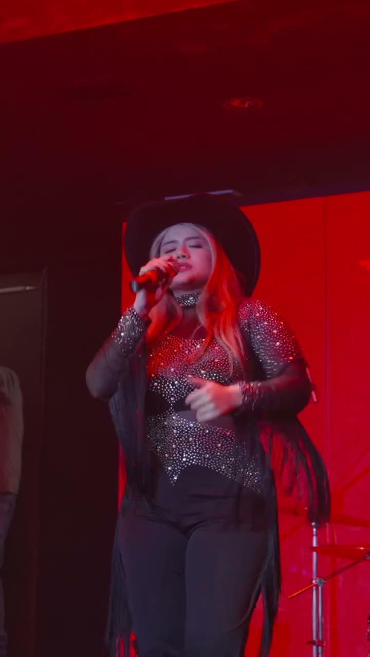 Valerie cantando con luces rojas en escenario